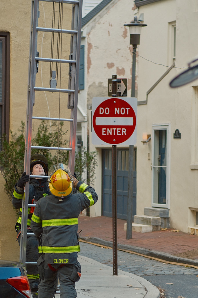 Two firemen setting up a ladder.
