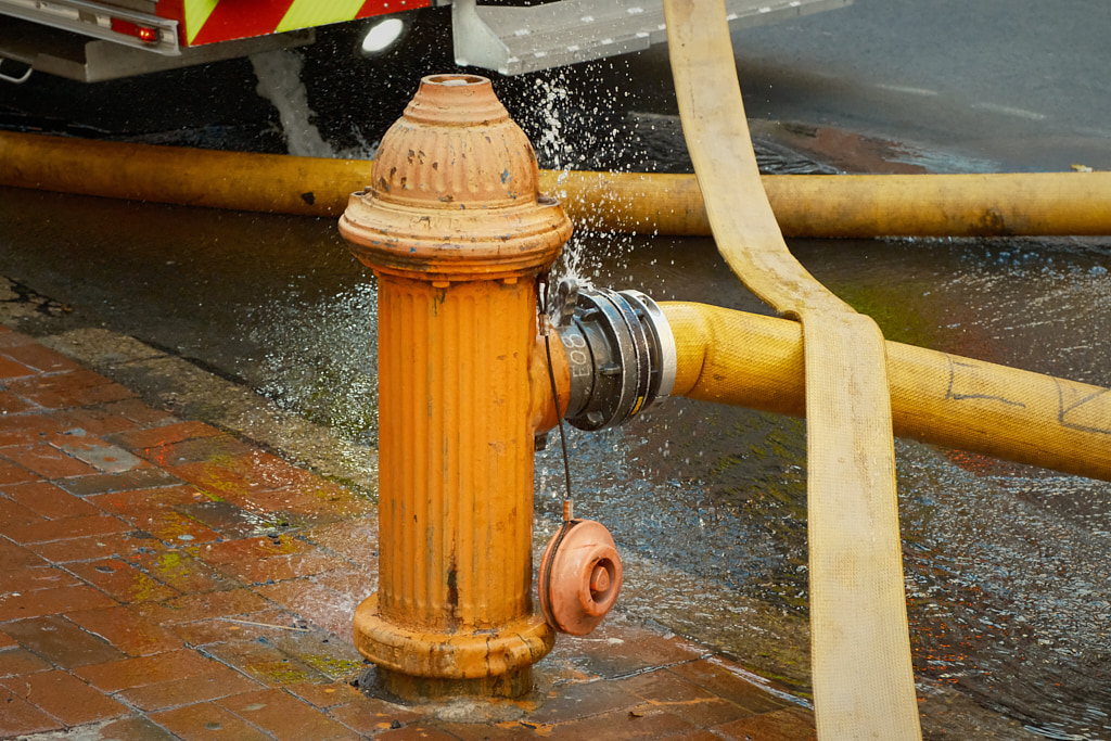 A fire hydrant pumps water into a firehose.