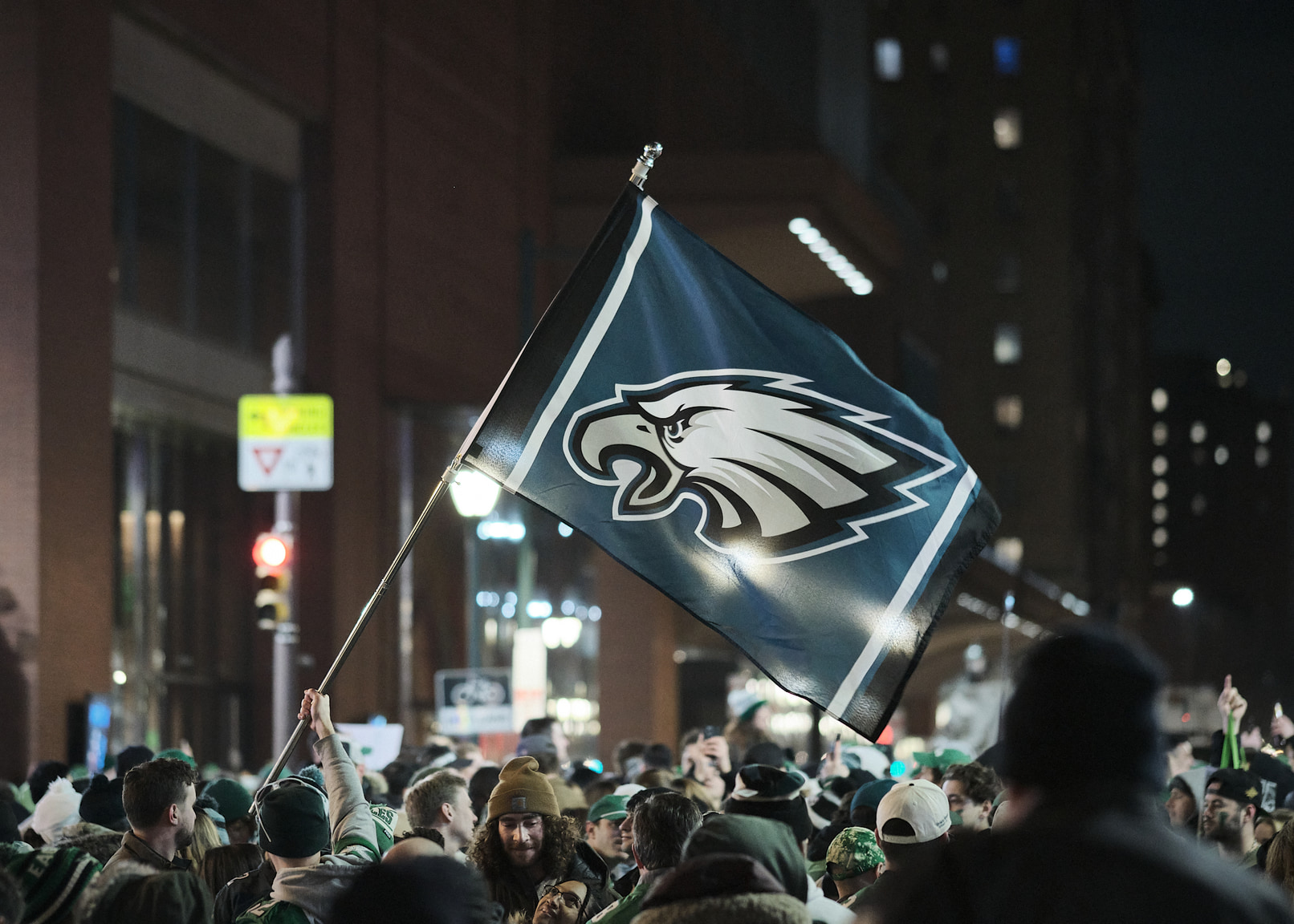 Eagles celebration on Broad Street featuring flag with team logo.
