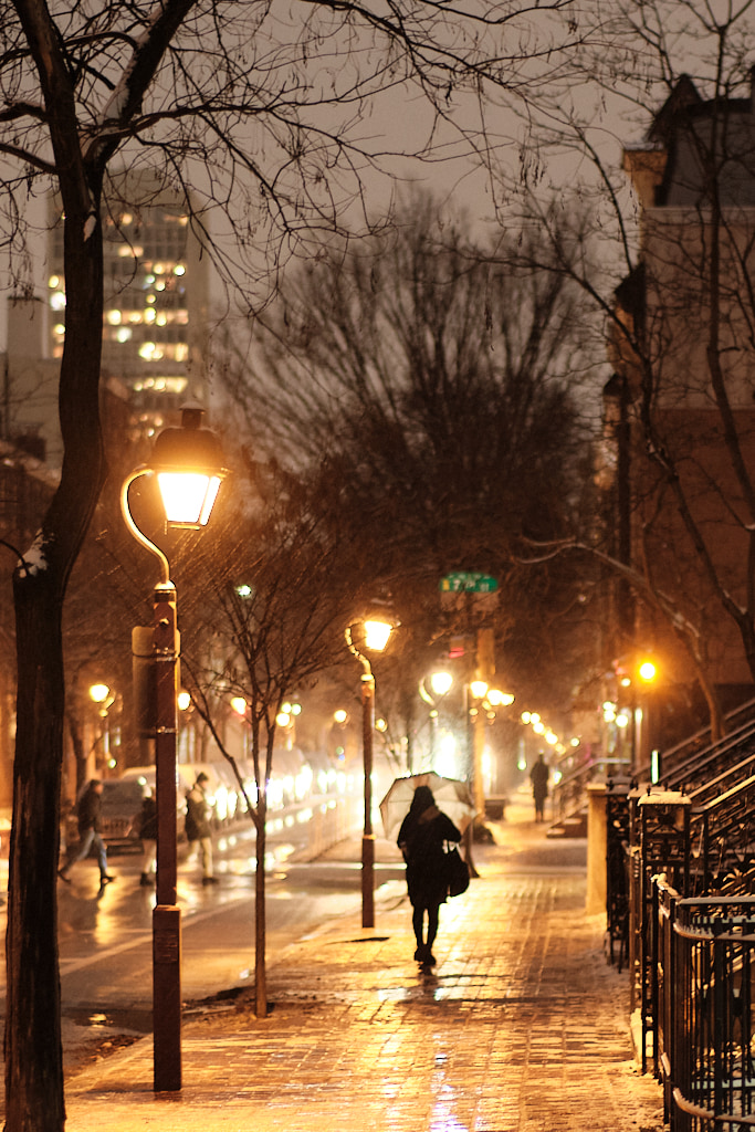 People walking city streets on snowy night.
