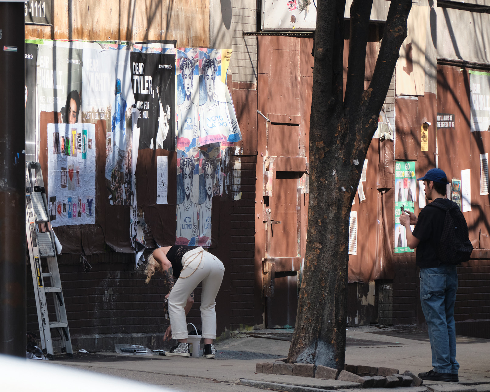 Wheatpaste artists applying a poster and admiring their work.