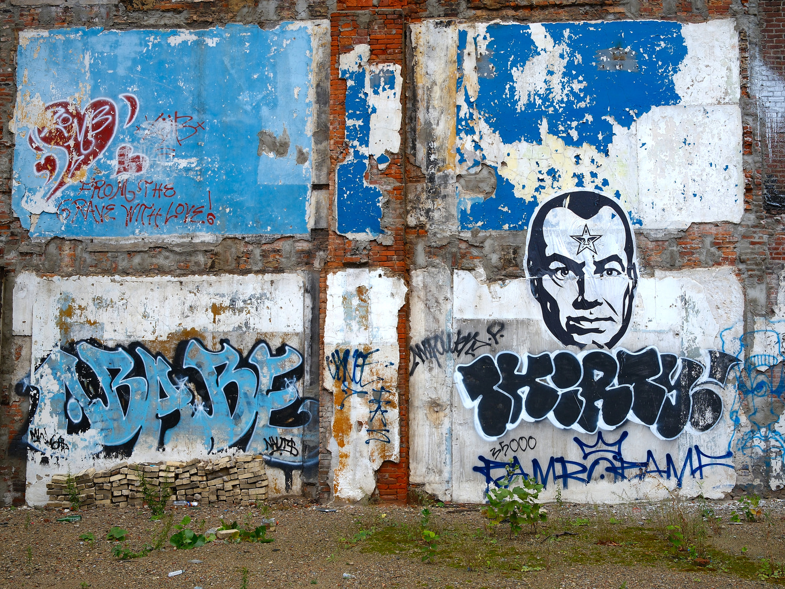 Graffiti and wheatpaste on a brick wall.