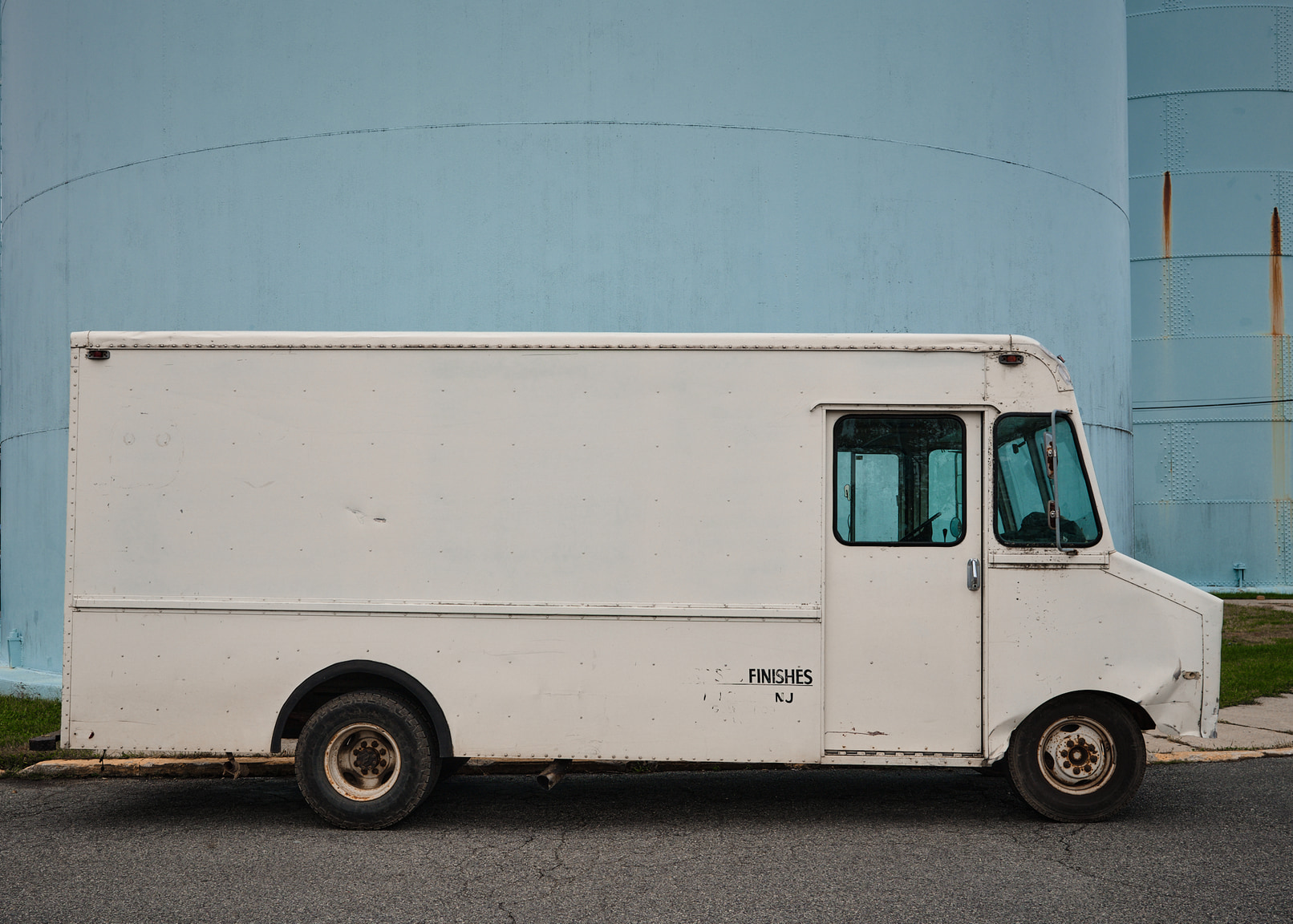 Old white box truck on blue background.