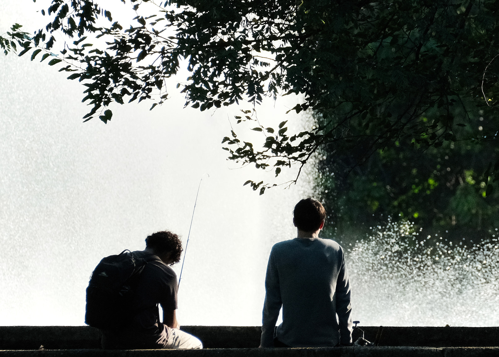 A couple of kids fishing by a fountain.